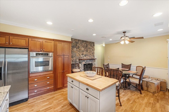 kitchen with stainless steel appliances, light wood finished floors, wood counters, and crown molding