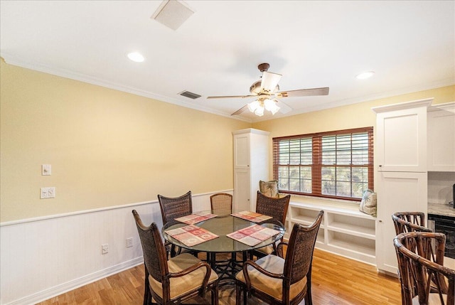 dining area featuring a wainscoted wall, visible vents, light wood-style flooring, and crown molding