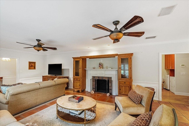 living room featuring washing machine and clothes dryer, visible vents, a brick fireplace, and a ceiling fan