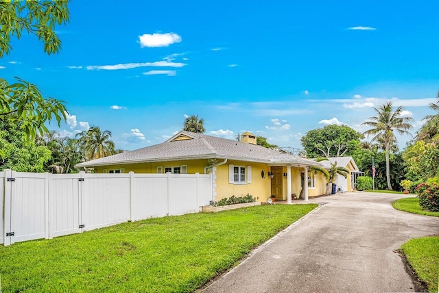 ranch-style house featuring a front lawn, fence, concrete driveway, stucco siding, and a gate