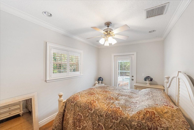 bedroom with visible vents, a textured ceiling, wood finished floors, crown molding, and access to exterior