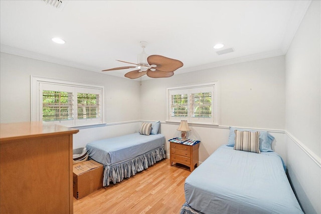 bedroom with wainscoting, multiple windows, light wood-style floors, and ornamental molding