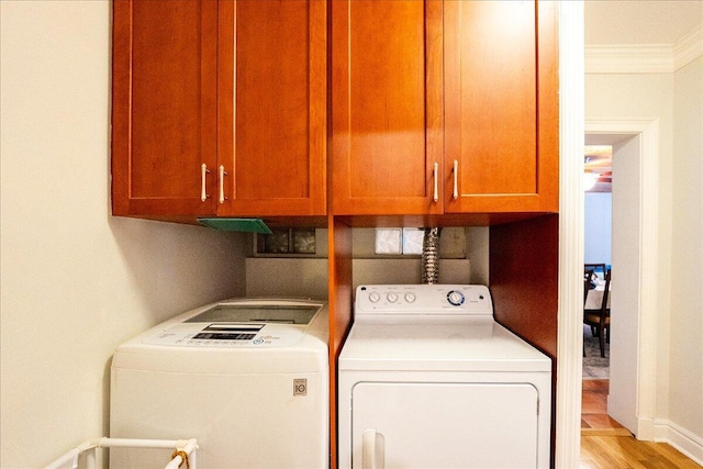 laundry area with washer and dryer, cabinet space, and ornamental molding