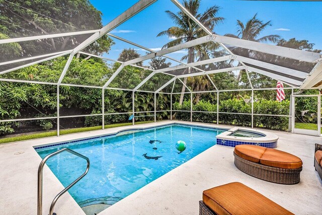 view of swimming pool with a patio, a pool with connected hot tub, and a lanai