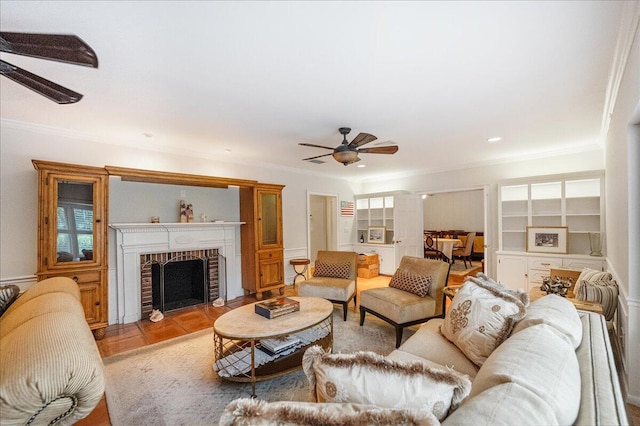 living room featuring a ceiling fan, crown molding, and a fireplace