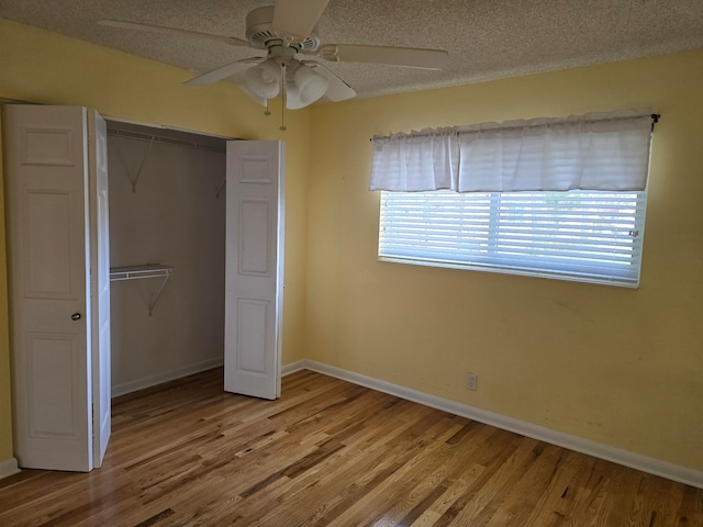 unfurnished bedroom featuring a textured ceiling, hardwood / wood-style floors, ceiling fan, and a closet