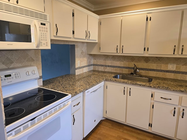 kitchen with white appliances, hardwood / wood-style floors, ornamental molding, white cabinetry, and dark stone counters