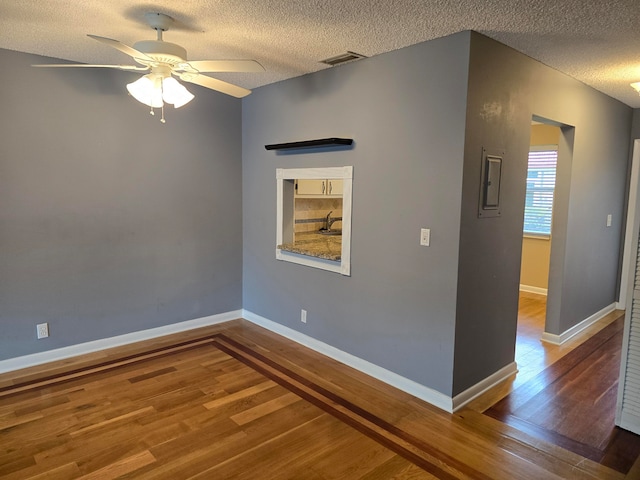 spare room featuring a textured ceiling, ceiling fan, sink, and wood-type flooring