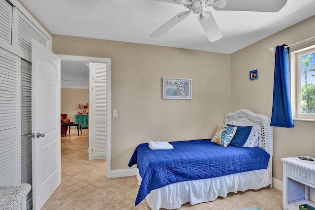 tiled bedroom with a closet, ceiling fan, and a textured ceiling