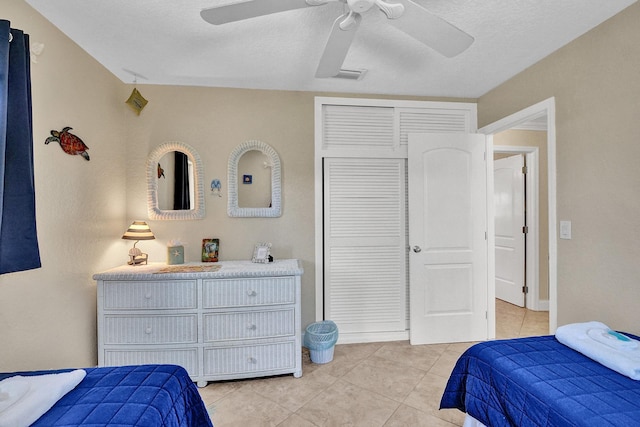 tiled bedroom with a textured ceiling, ceiling fan, and a closet