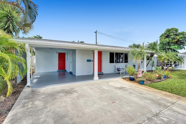 single story home with covered porch, a front lawn, and a carport