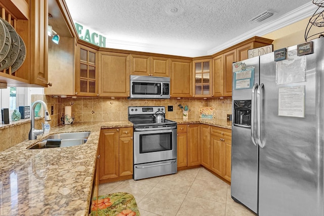 kitchen featuring a textured ceiling, stainless steel appliances, sink, ornamental molding, and light stone counters