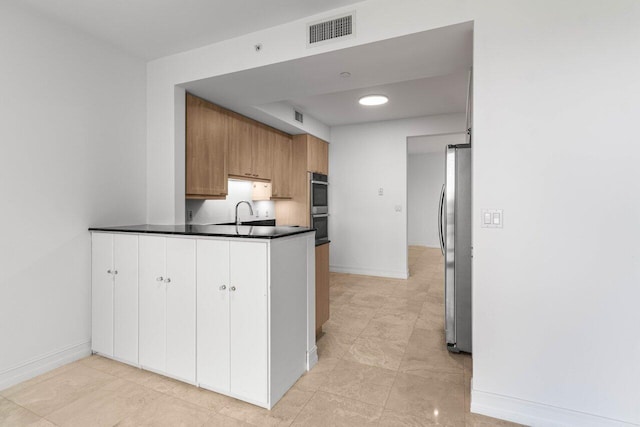 kitchen featuring stainless steel appliances, dark countertops, visible vents, and brown cabinets