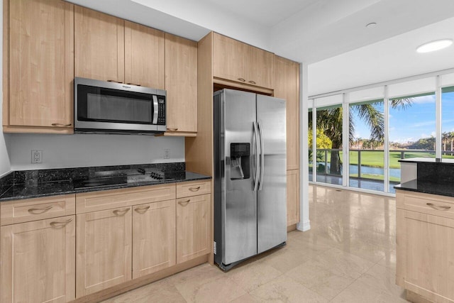 kitchen featuring stainless steel appliances, dark stone counters, and light brown cabinetry