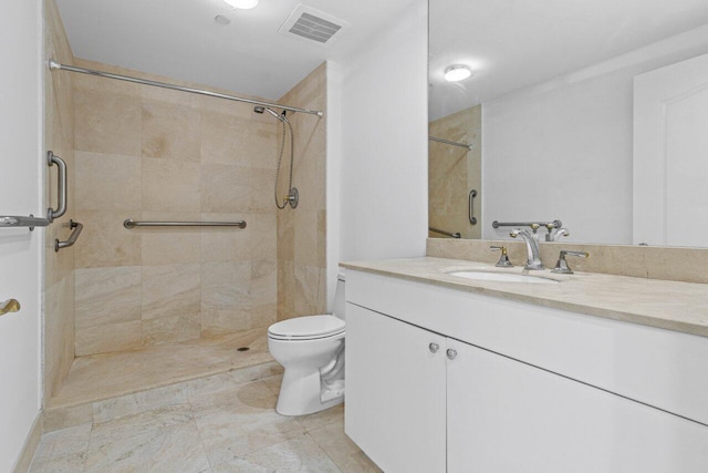 bathroom with toilet, vanity, visible vents, and a tile shower