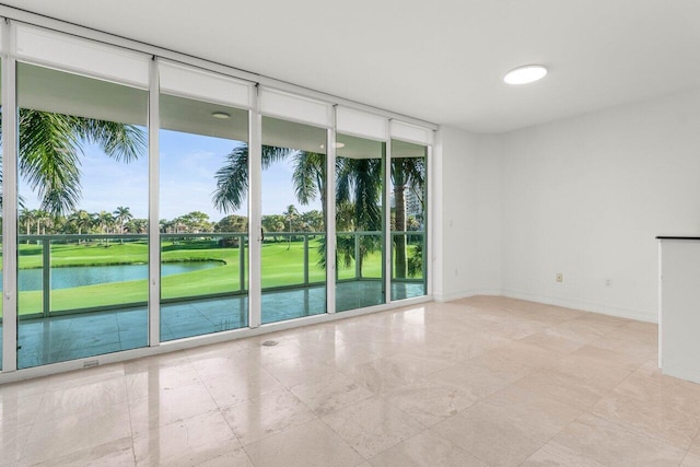 spare room with a water view, baseboards, and a wall of windows