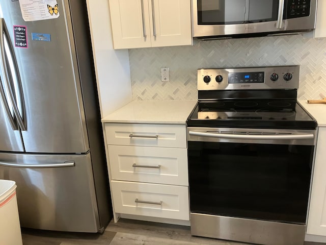 kitchen featuring light hardwood / wood-style flooring, stainless steel appliances, backsplash, and white cabinetry