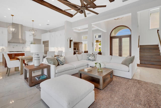 living room with beam ceiling, ceiling fan, and a towering ceiling