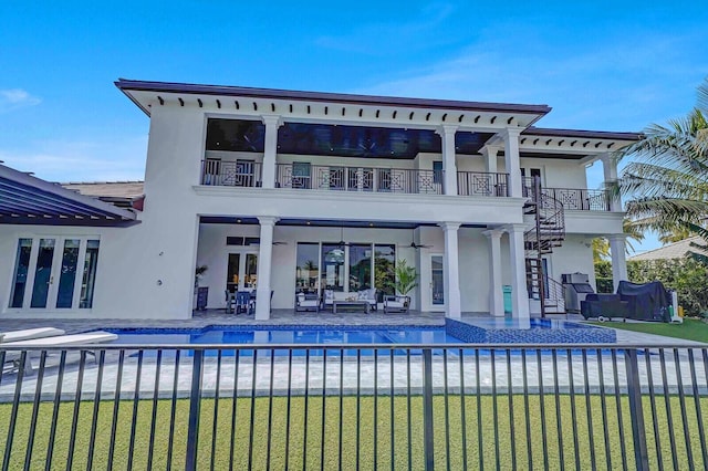 rear view of property with a balcony, a fenced in pool, and a patio area