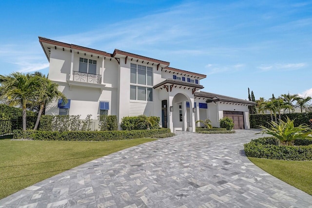 view of front of house with a balcony, a front lawn, and a garage