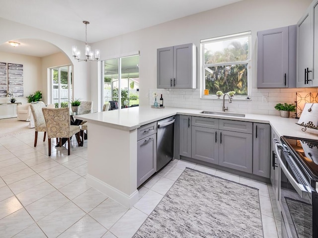 kitchen featuring tasteful backsplash, kitchen peninsula, sink, and appliances with stainless steel finishes