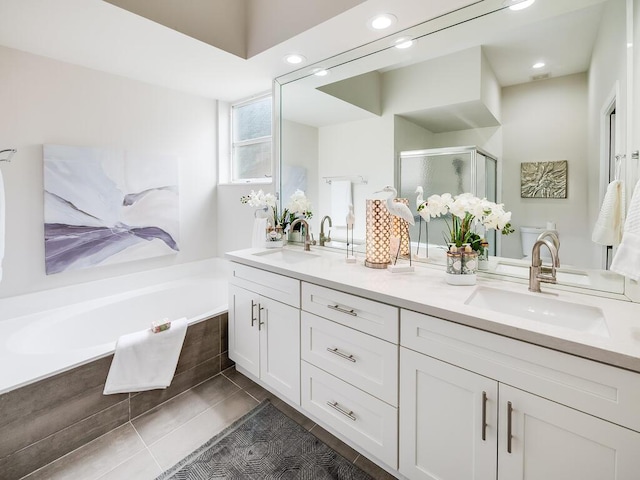 bathroom featuring plus walk in shower, vanity, and tile patterned flooring