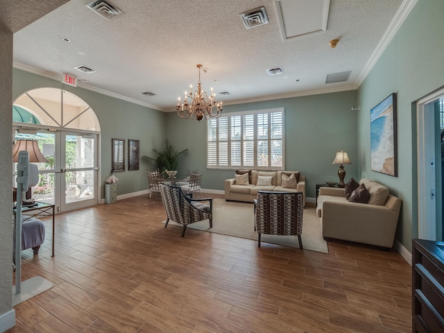 living room with ornamental molding, a textured ceiling, an inviting chandelier, and a healthy amount of sunlight