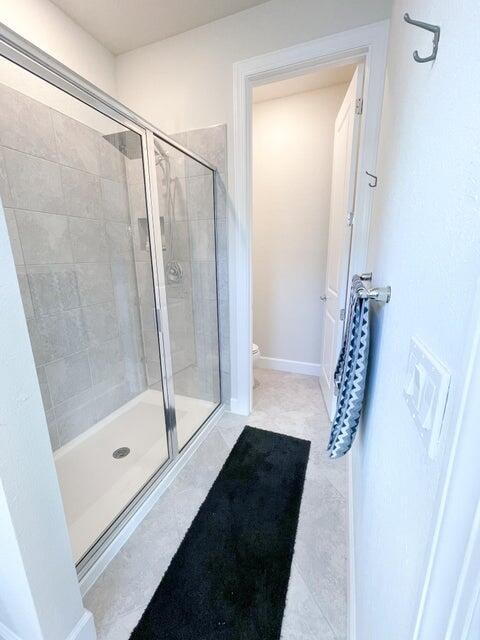 bathroom with toilet, walk in shower, and tile patterned floors