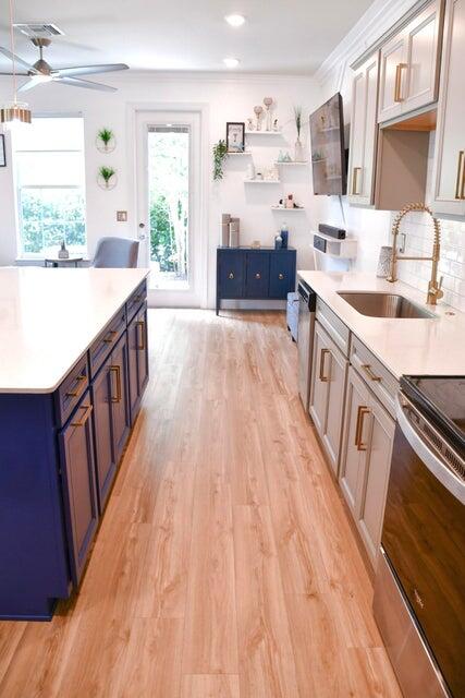 kitchen with blue cabinetry, appliances with stainless steel finishes, light hardwood / wood-style floors, sink, and ceiling fan