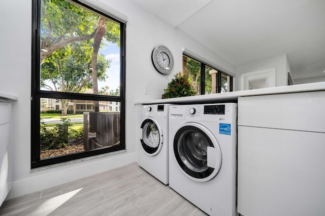 laundry room with plenty of natural light, light hardwood / wood-style flooring, and washer and dryer