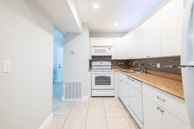 kitchen featuring decorative backsplash, white cabinets, white appliances, light tile patterned floors, and sink