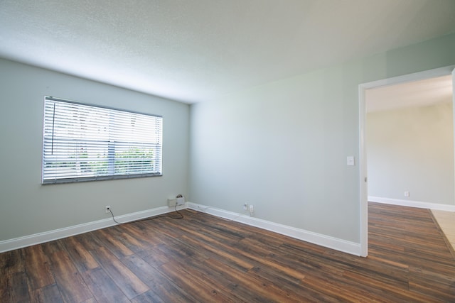 empty room featuring a textured ceiling and dark wood-type flooring