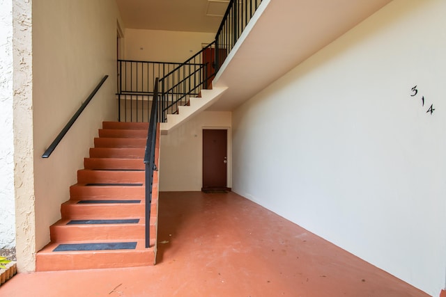staircase with concrete flooring and a high ceiling