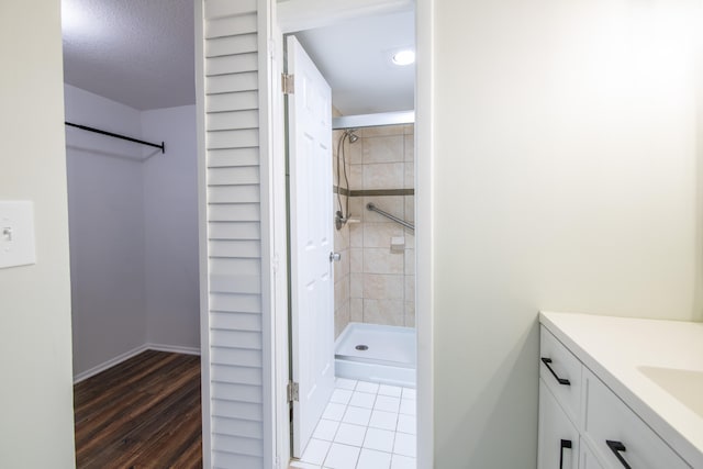 bathroom featuring vanity, a textured ceiling, hardwood / wood-style floors, and tiled shower