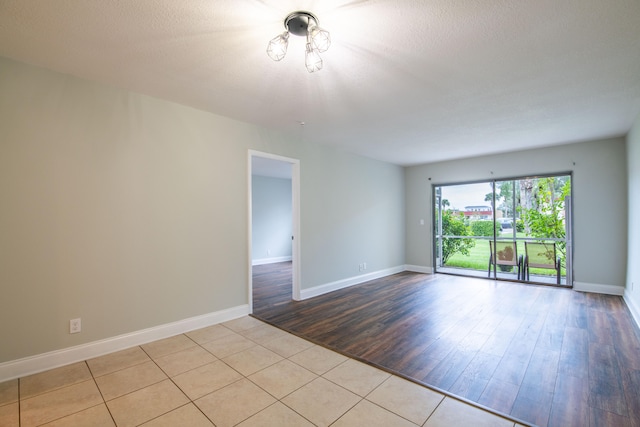 spare room with light wood-type flooring and a textured ceiling