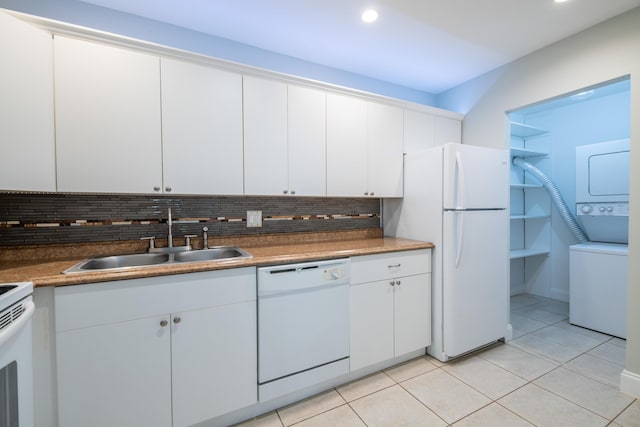 kitchen with decorative backsplash, light tile patterned flooring, white appliances, a sink, and stacked washing maching and dryer