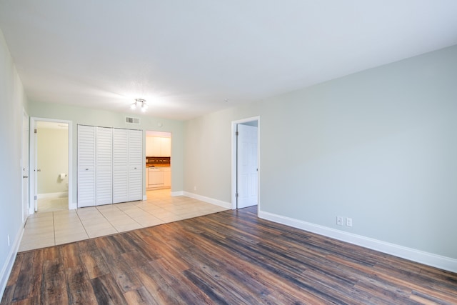 unfurnished bedroom with a closet, ensuite bath, and light hardwood / wood-style floors