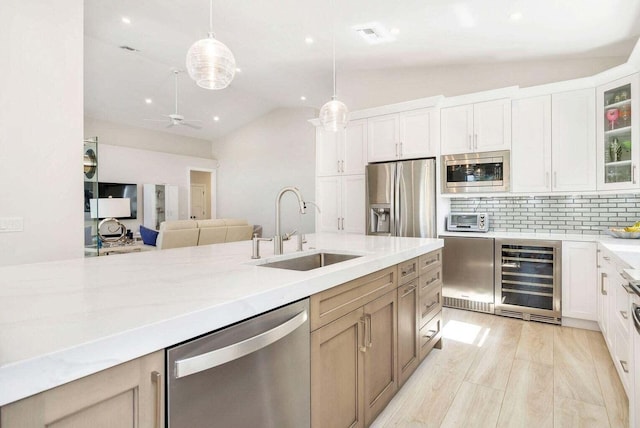 kitchen featuring decorative light fixtures, beverage cooler, appliances with stainless steel finishes, sink, and white cabinetry