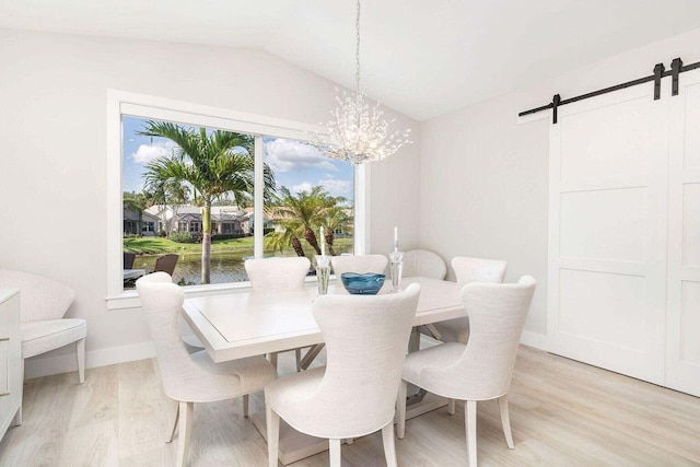 dining area featuring vaulted ceiling, a barn door, light hardwood / wood-style flooring, a notable chandelier, and a water view