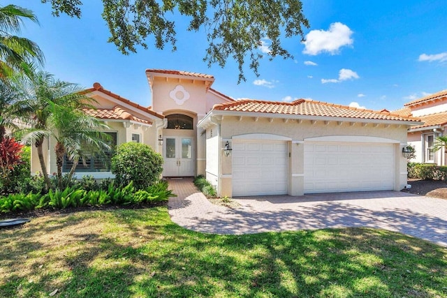 mediterranean / spanish home featuring a garage and a front lawn