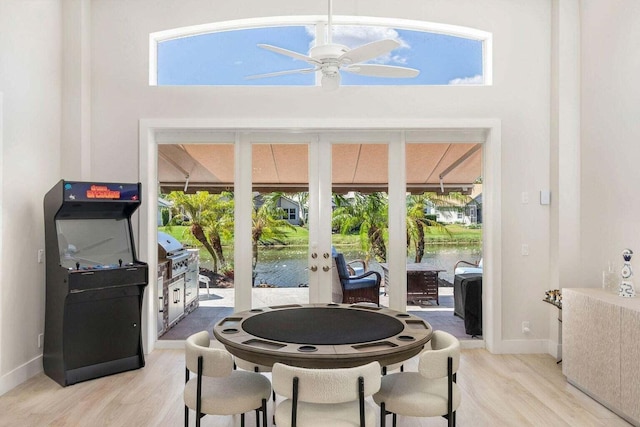 dining space with a water view, french doors, ceiling fan, and light hardwood / wood-style flooring