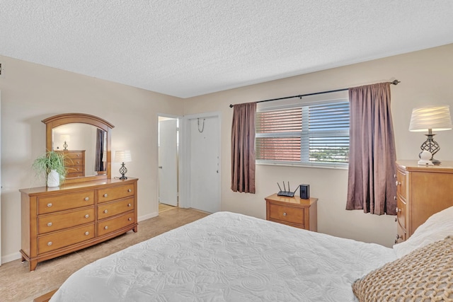 bedroom with light colored carpet and a textured ceiling