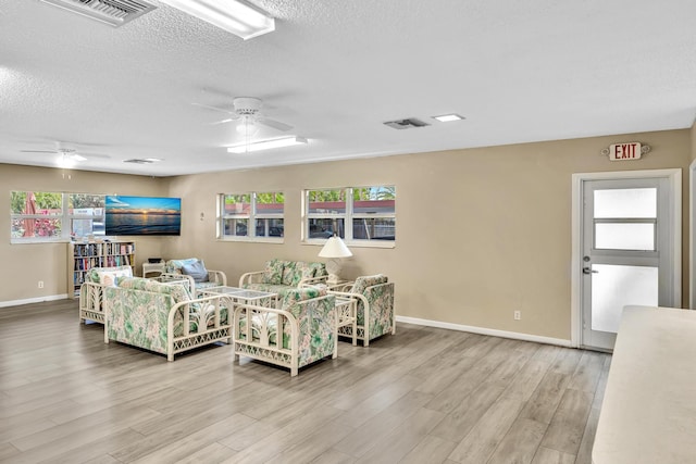 living room featuring a textured ceiling, plenty of natural light, ceiling fan, and wood-type flooring