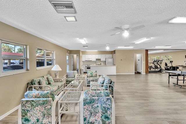 living room featuring ceiling fan, a wealth of natural light, and light hardwood / wood-style flooring