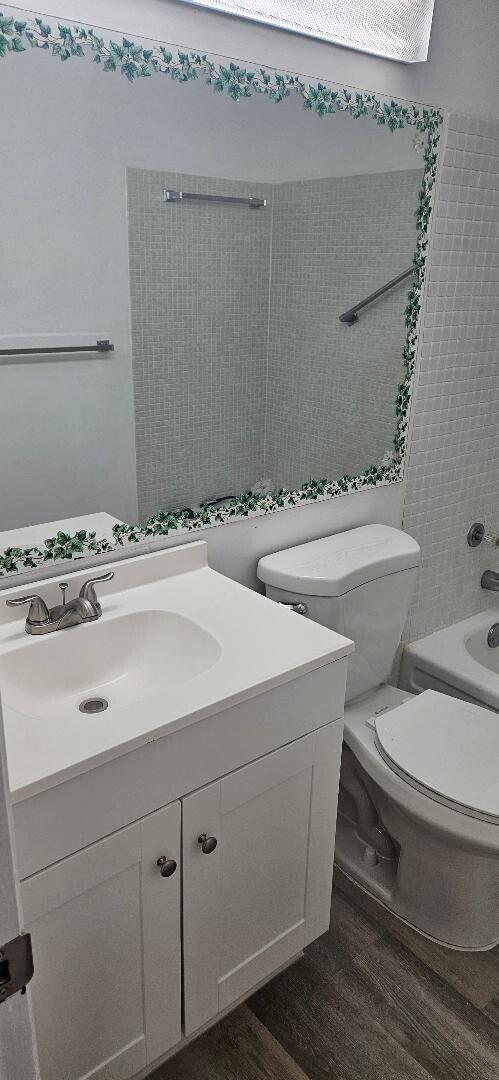 full bathroom with vanity, toilet, wood-type flooring, and bathing tub / shower combination