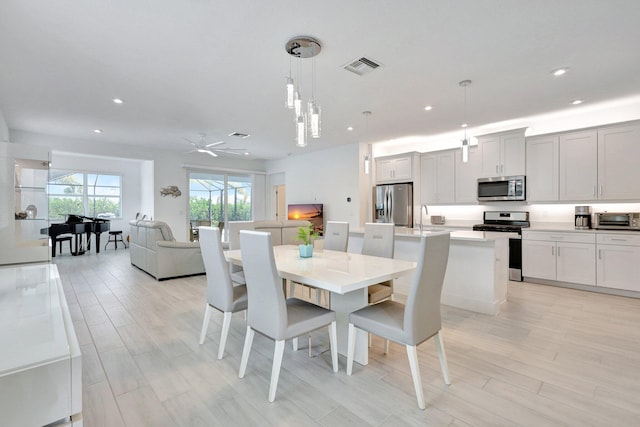 dining space with ceiling fan, sink, and light hardwood / wood-style floors