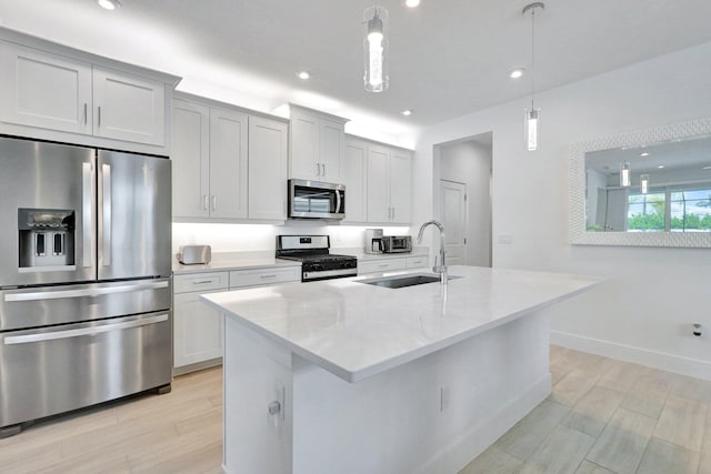 kitchen featuring white cabinets, decorative light fixtures, stainless steel appliances, and a kitchen island with sink