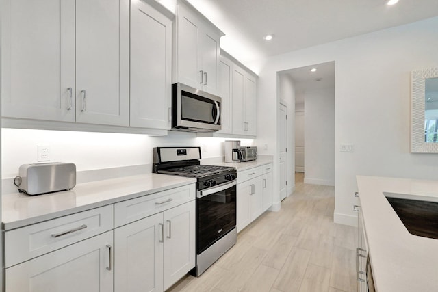 kitchen featuring appliances with stainless steel finishes, light hardwood / wood-style floors, white cabinetry, and sink