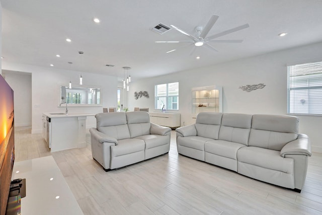 living room featuring ceiling fan, light wood-type flooring, and sink