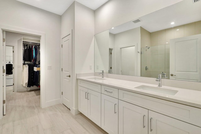 bathroom with vanity, washer / dryer, and a shower with shower door